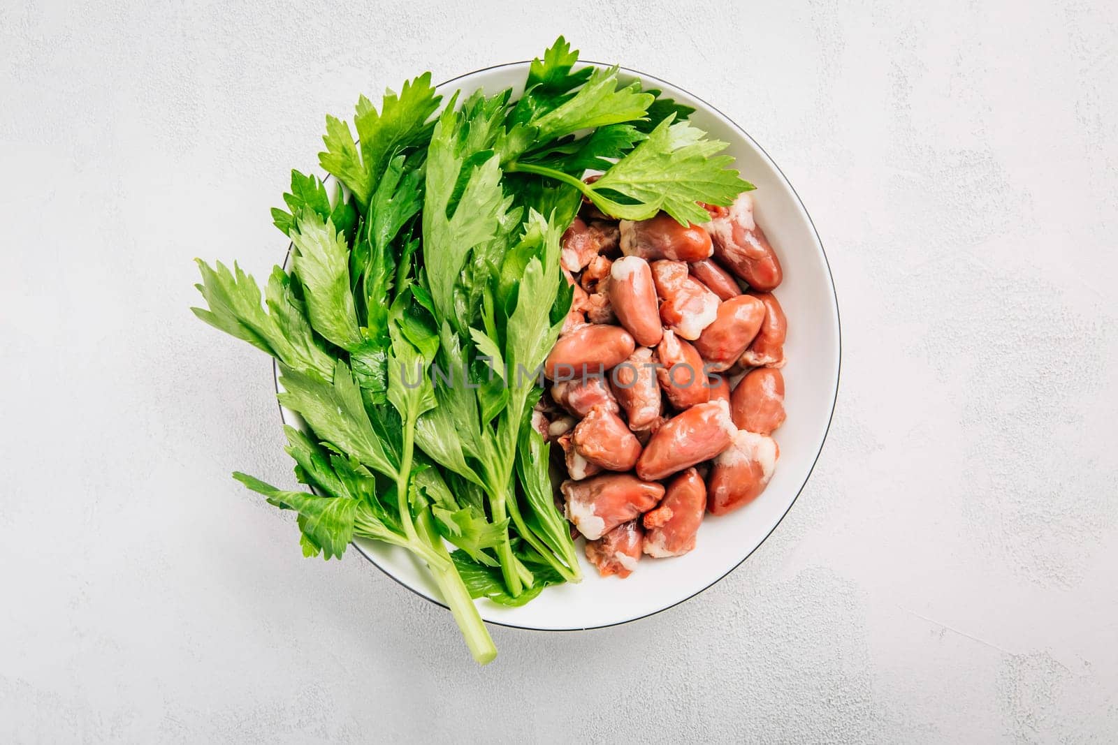 Fresh raw chicken hearts with celery leaves, reading for cooking