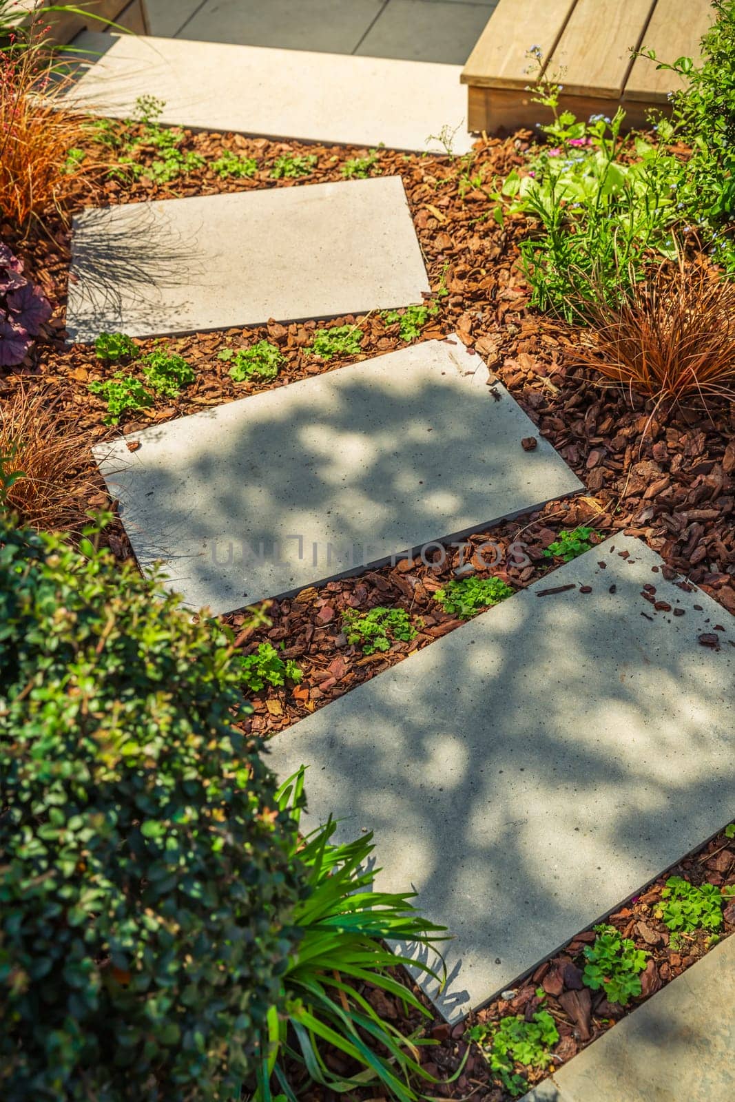 Detail of garden path with stone slabs with bark mulch and native plants. Landscaping and gardening concept.