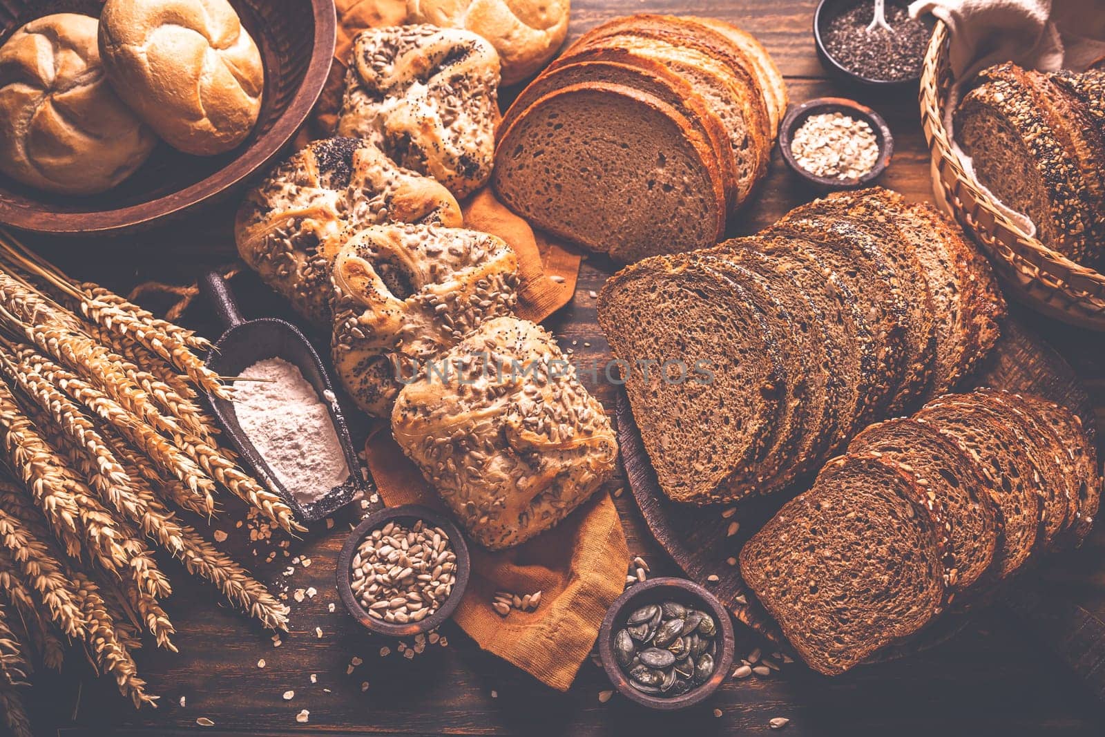 Assortment of different kind of cereal bakery - bread, pasties, buns, with healthy seeds on wooden background