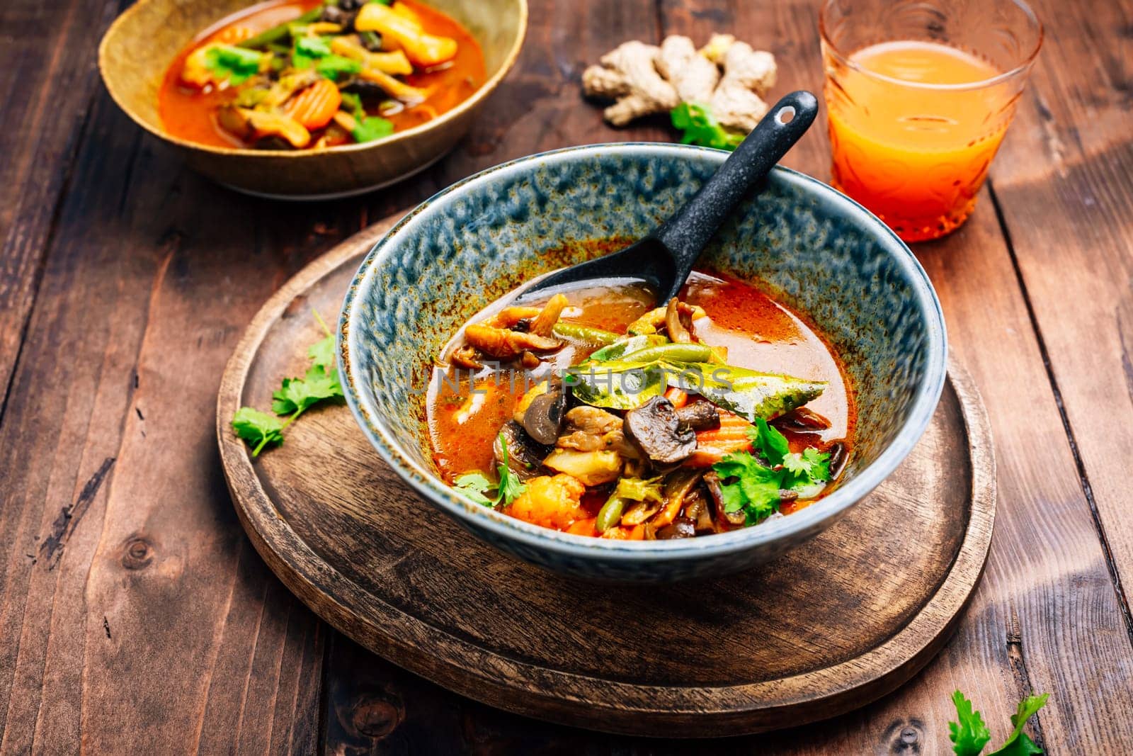 Thai red vegetarian curry with mushrooms and vegetables on wooden table