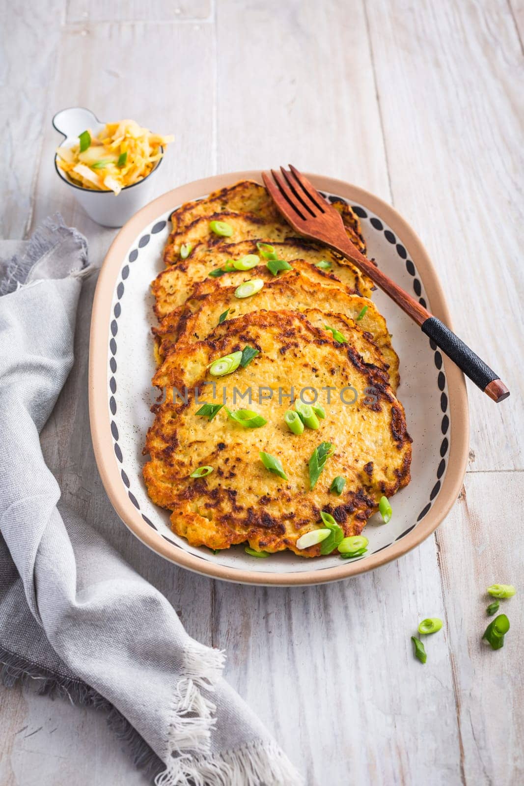 Homemade potato pancakes (Kartoffelpuffer) with cabbage salad and green onions