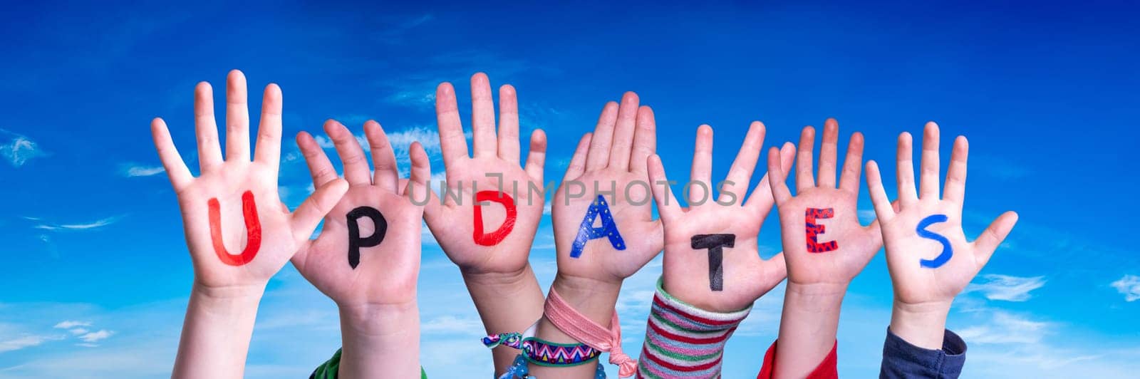 Children Hands Building Colorful English Word Updates. Blue Sky As Background.