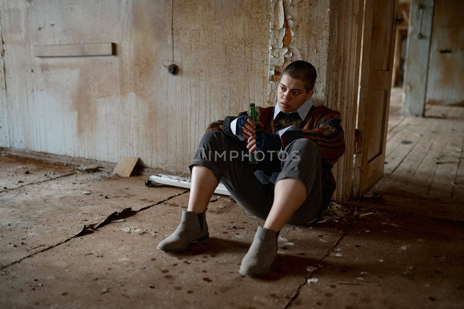 Unhappy unemployment homeless woman drinking beer sitting on floor dreaming about best life