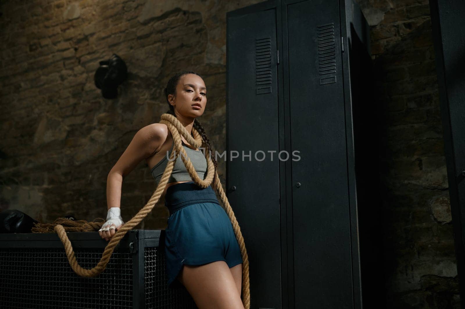 Fashion gorgeous woman boxer wrapped in rope on loft gym background. Boxing concept