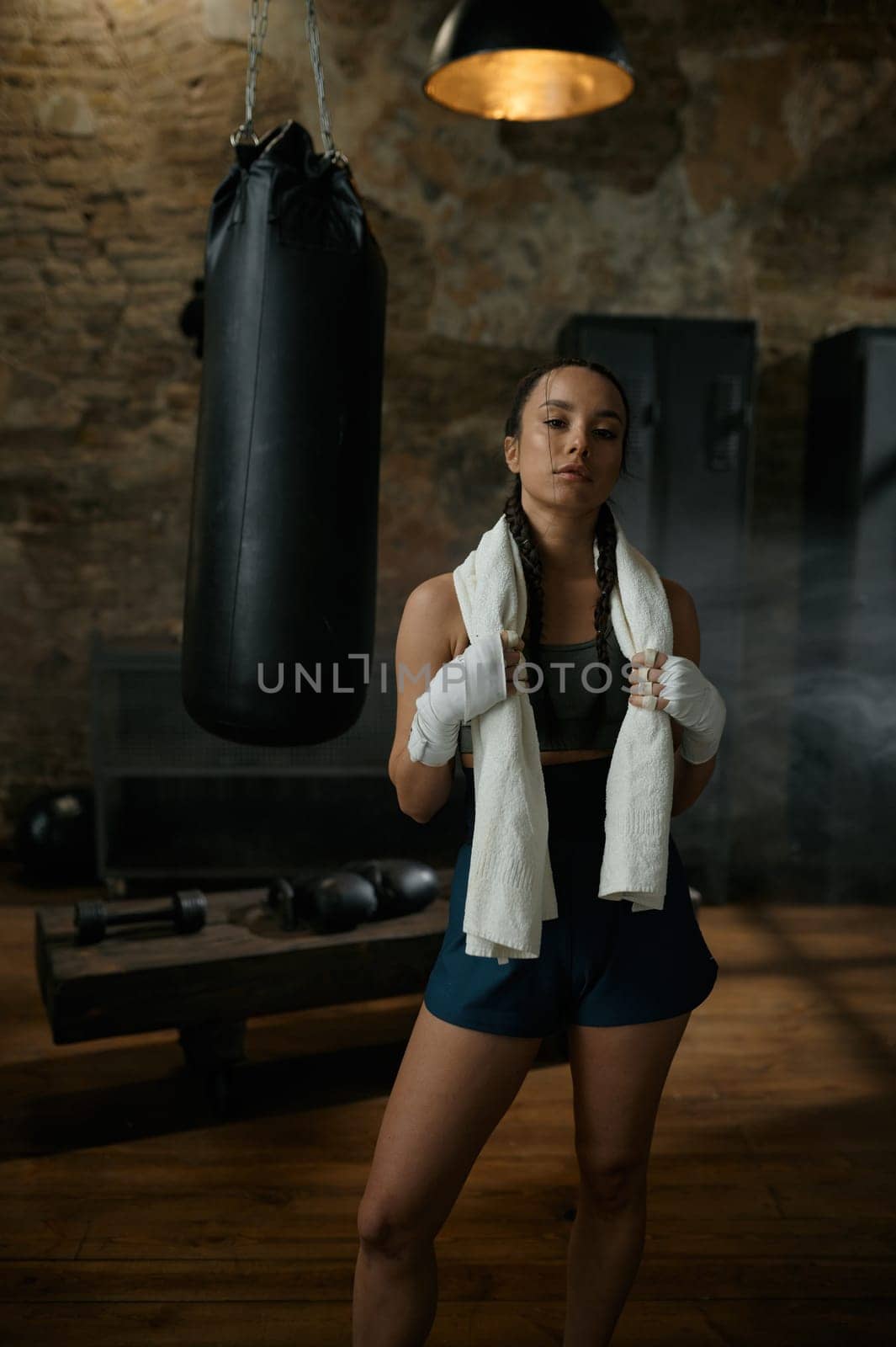 Satisfied woman boxer with towel on shoulders looking at camera. Sport, hobby and personal achievement concept