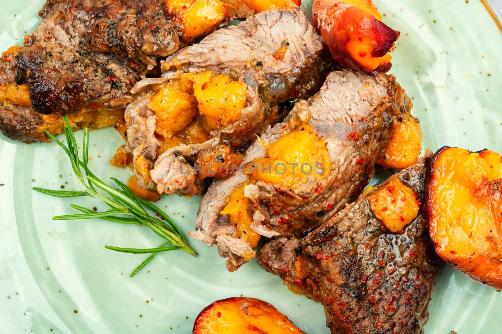 Succulent beef steak with peach in fruit marinade. Close-up.