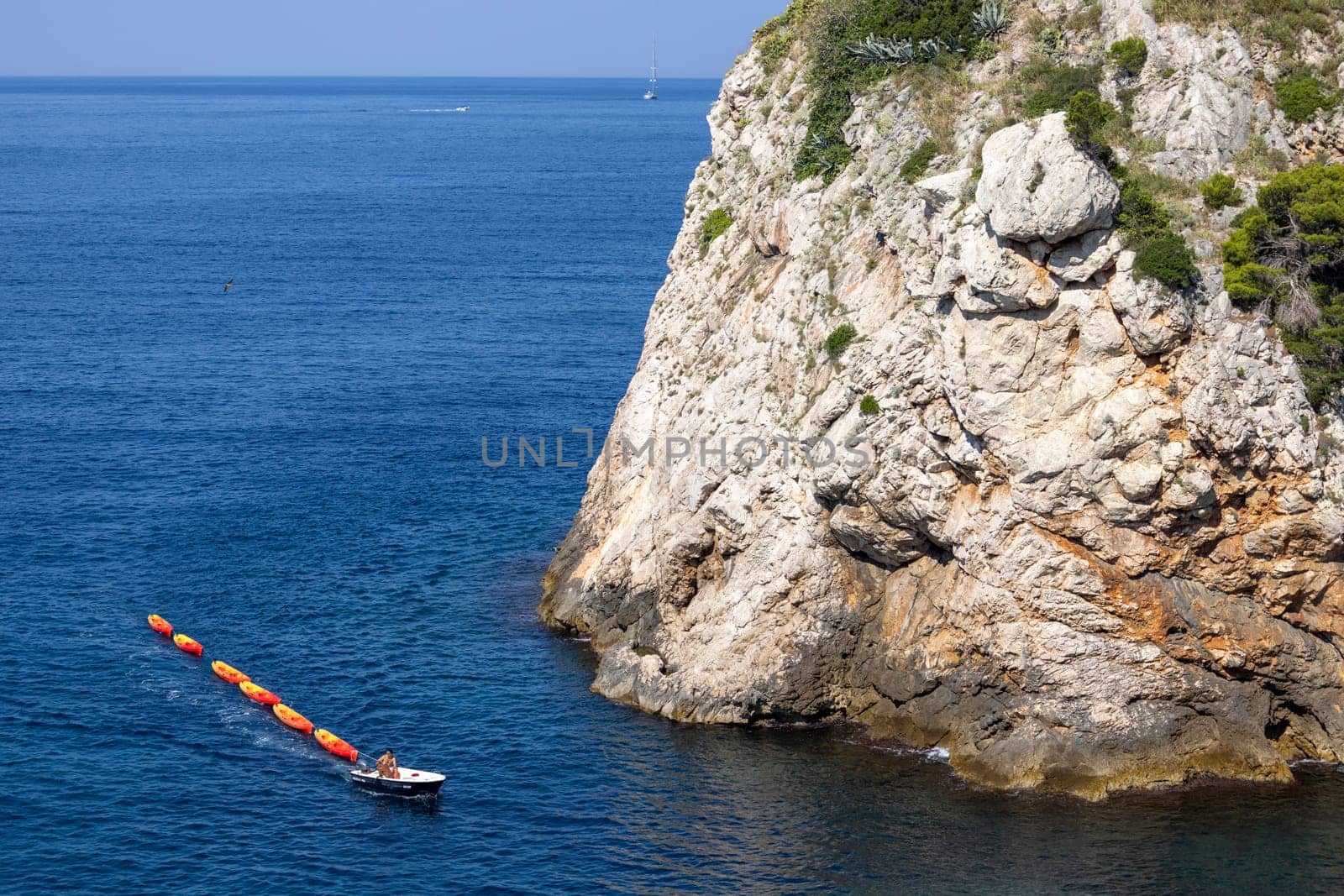 Dubrovnik, Croatia - June 27, 2023: Transportation of colorful kayaks for tourists by water on the Adriatic Sea to the West Harbour next to Fort Lovrijenac and City Walls