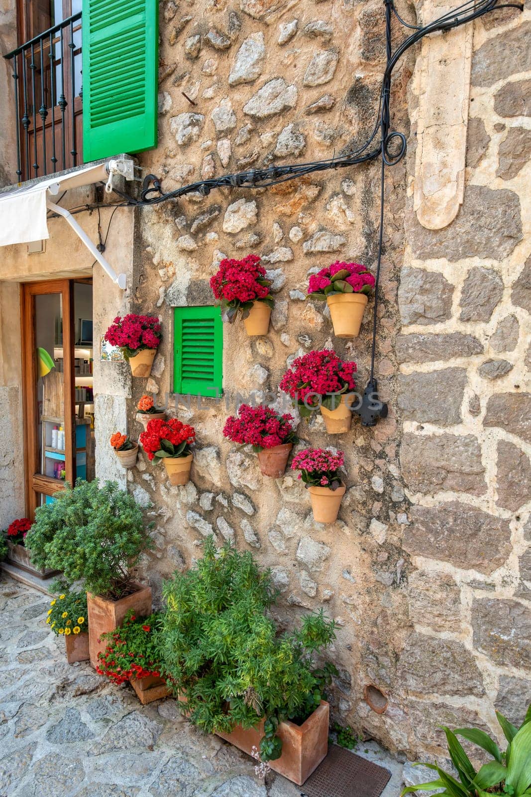 Narrow street in the Valldemossa with lots of ubiquitous flowers. Architectural treasures - Magic of Valldemossa's historic center and its Mediterranean architecture. Balearic Islands Mallorca Spain.