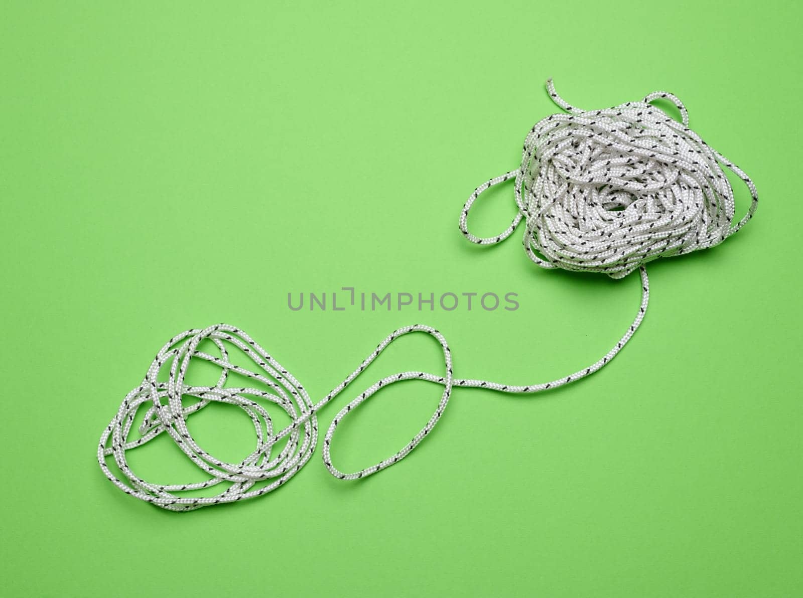 White laundry rope on a green background, top view
