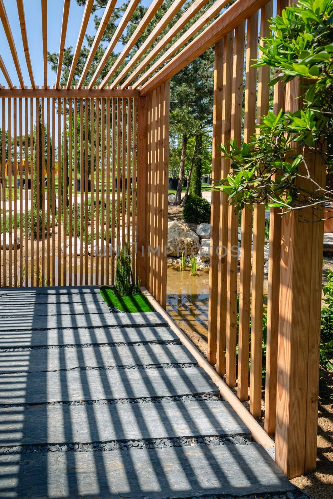 Modern wooden arbor. Modern wooden gazebo in courtyard, backyard. Urban gazebo, relaxing garden design.
