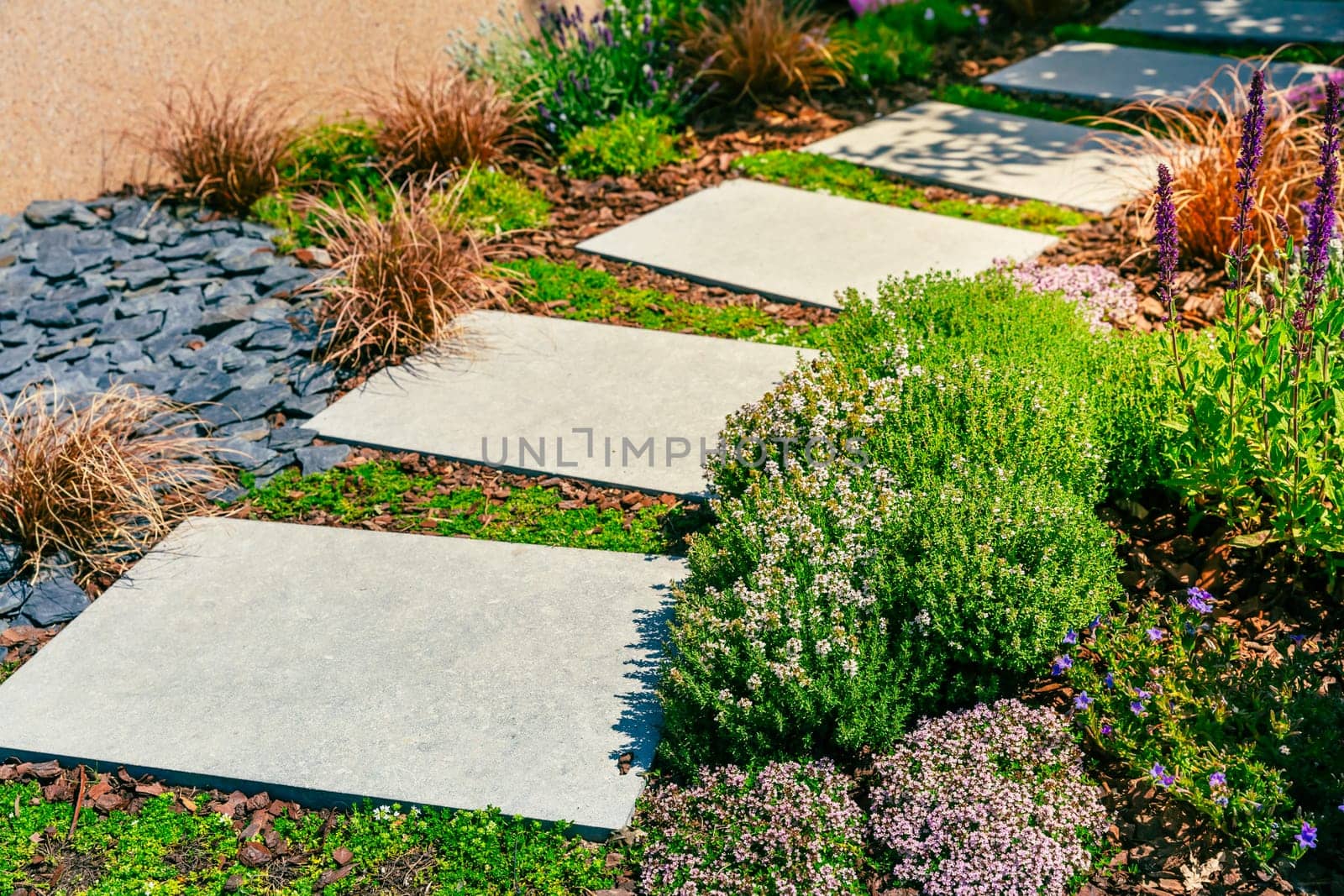 Detail of garden path with stone slabs with bark mulch and native plants. Landscaping and gardening concept.