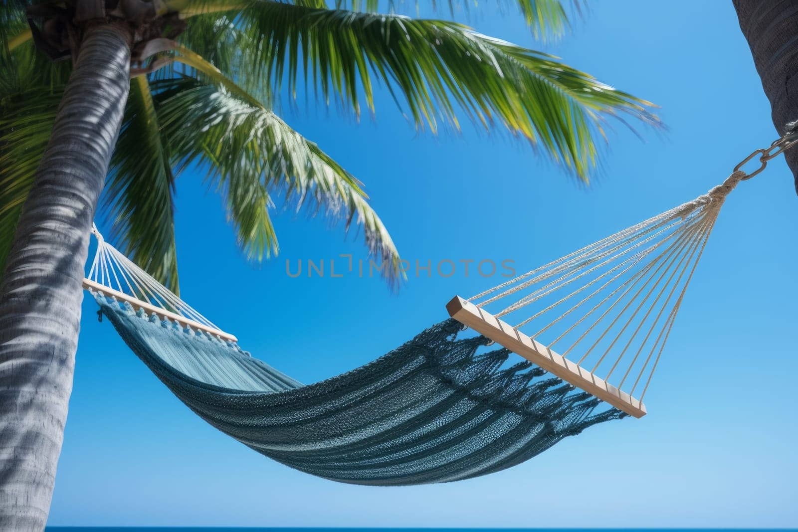A hammock hanging between two palm trees on a beach