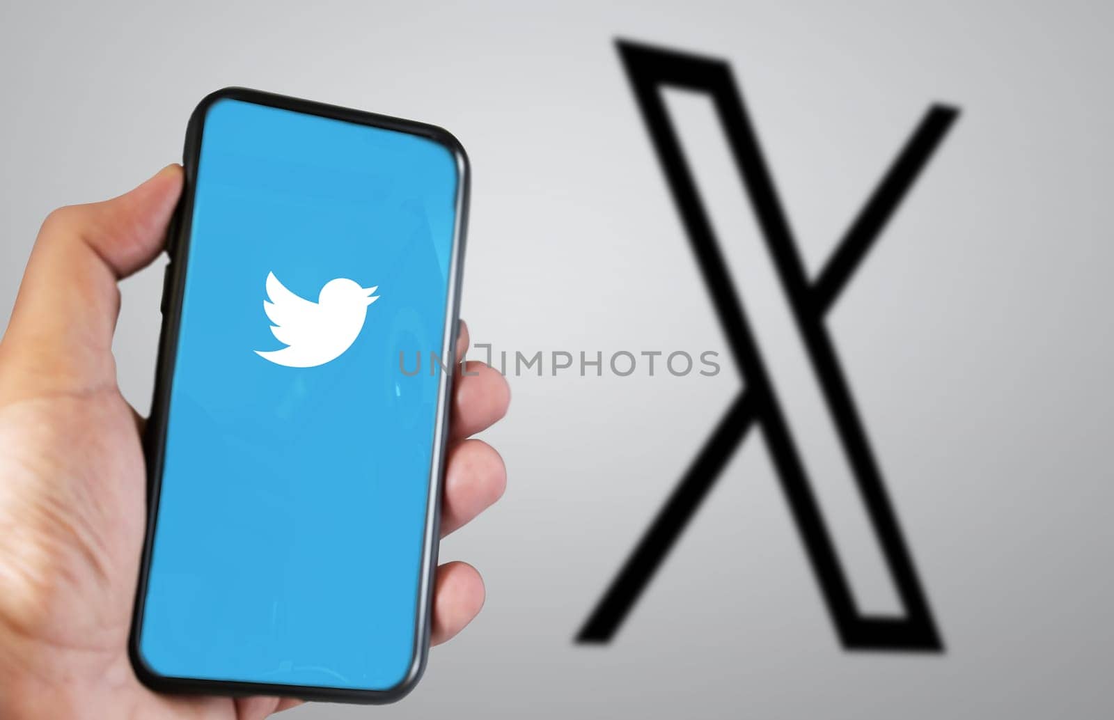 San Francisco, US, July 23 2023: hand holding a mobile phone with the Twitter X application on the screen. The new X logo blurred in the background. Illustrative editorial