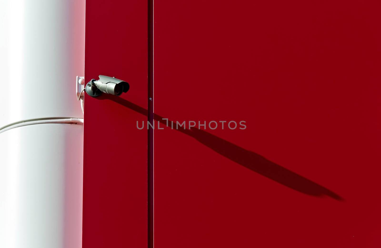 High-tech infrared security camera on the background of a red wall.