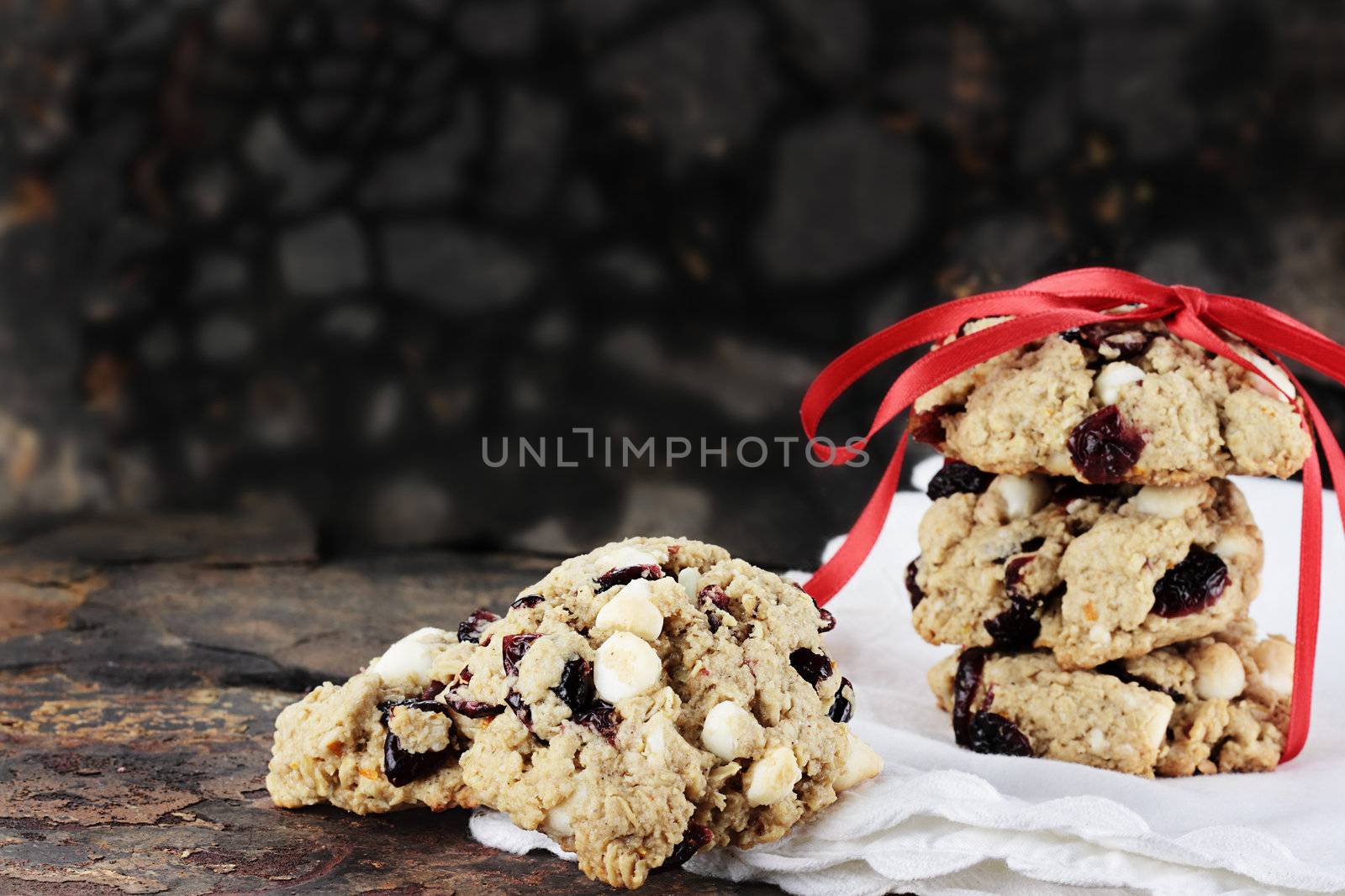 Cranberry, oats and white chocolate chip cookies over a rustic background.

