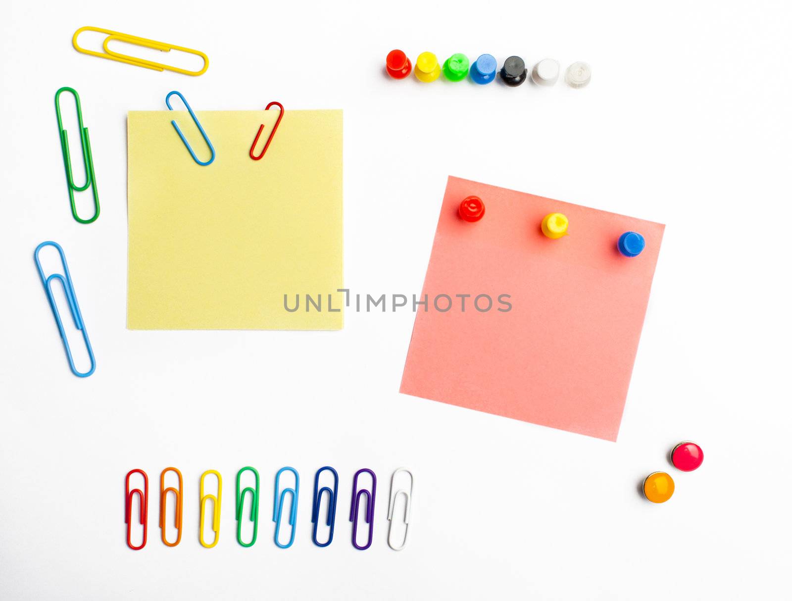 Rainbow paperclips and push pins arranged with sticky notes