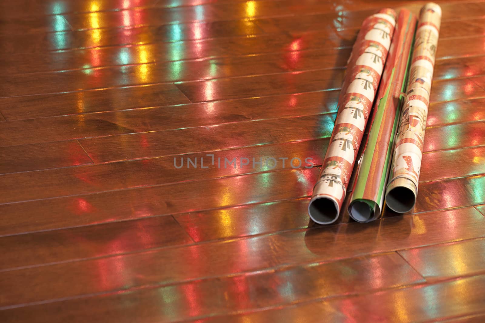 Close-up shot of shiny rolled up wrapping paper with light reflection on wooden plank.