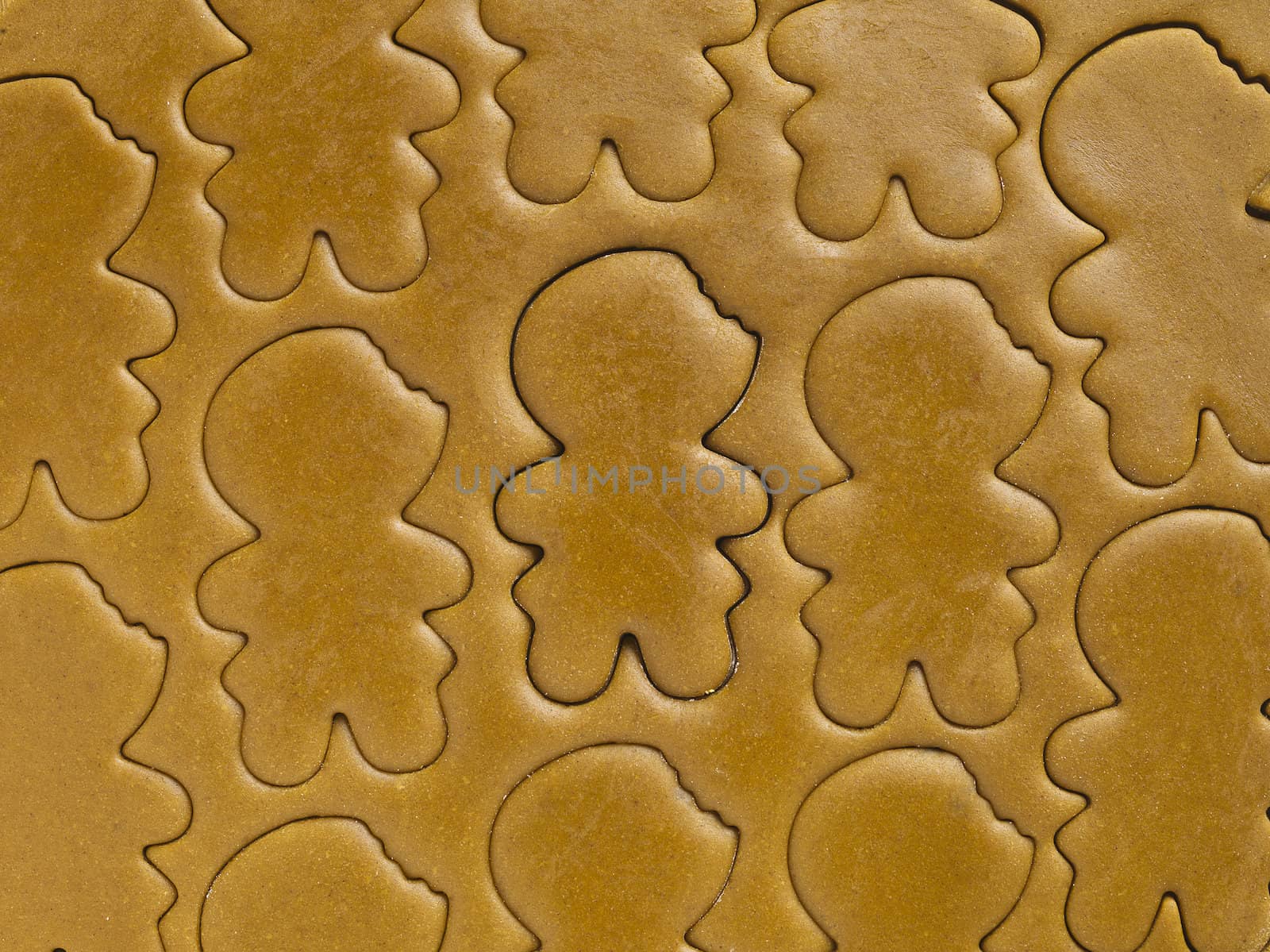 Close-up shot of gingerbread man shapes on gingerbread dough.