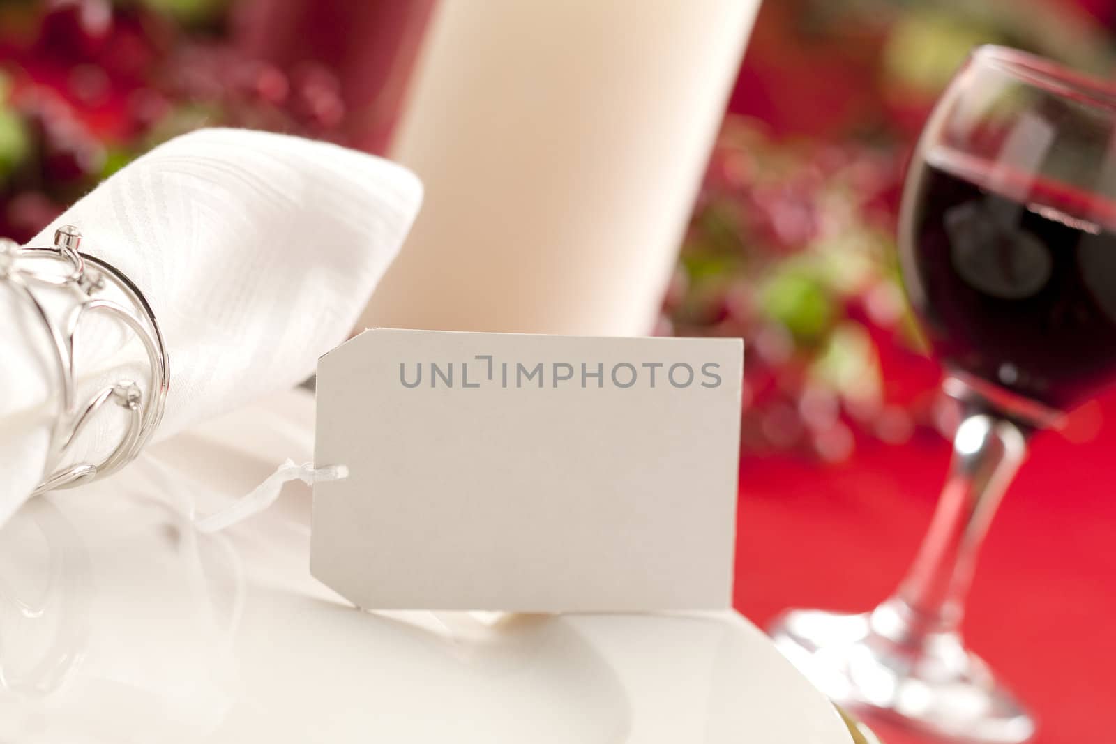 Image of a white plate with table napkin and a blurred wine glass on the side on holiday season