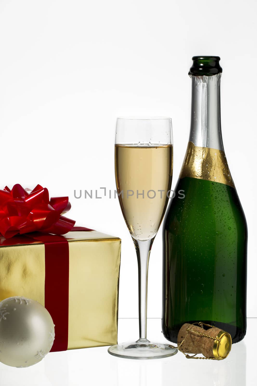Champagne flute and bottle with Christmas gift and cork on white background
