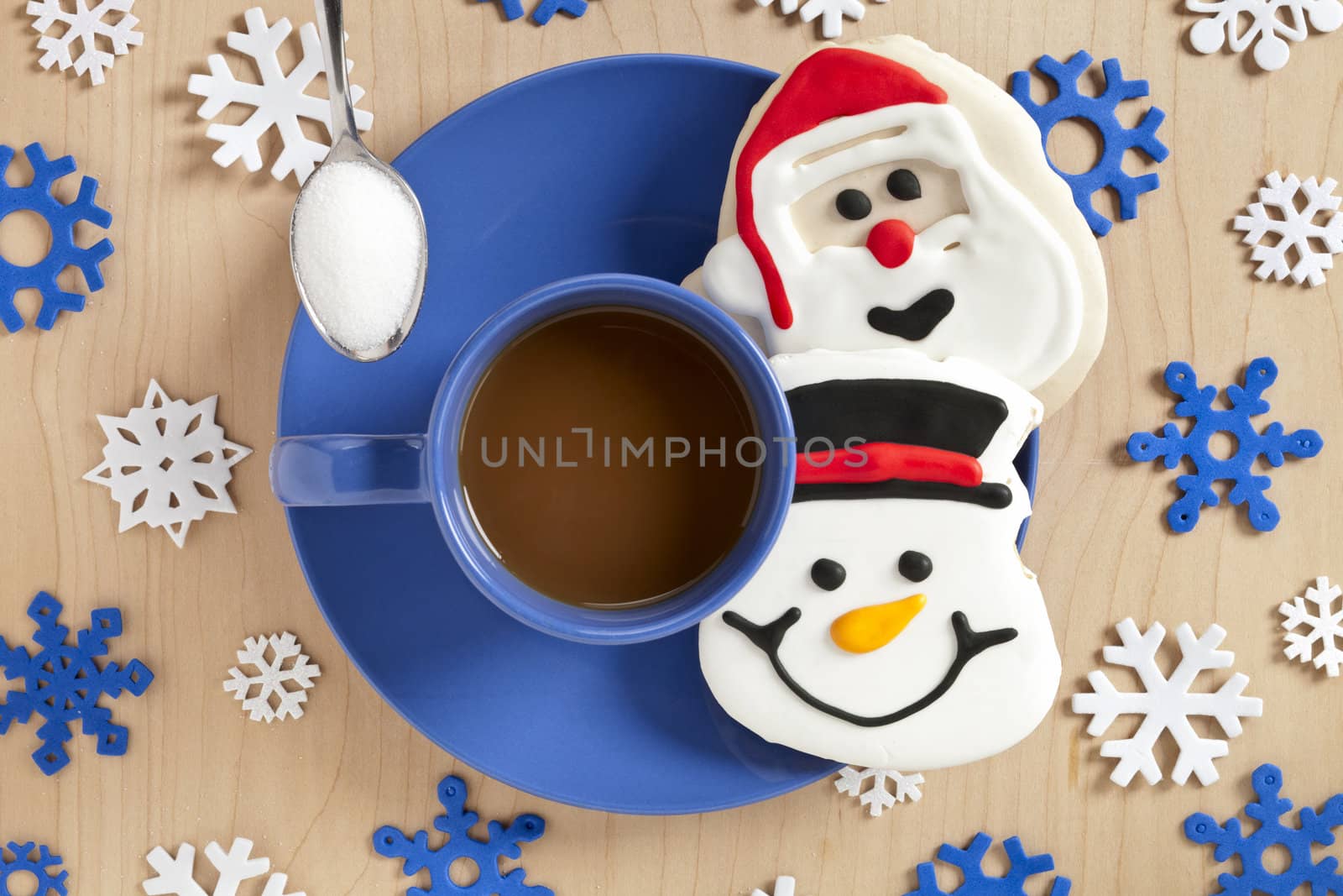 Close-up top view of a blue coffee cup Christmas candies and snowflake design on wooden plank.