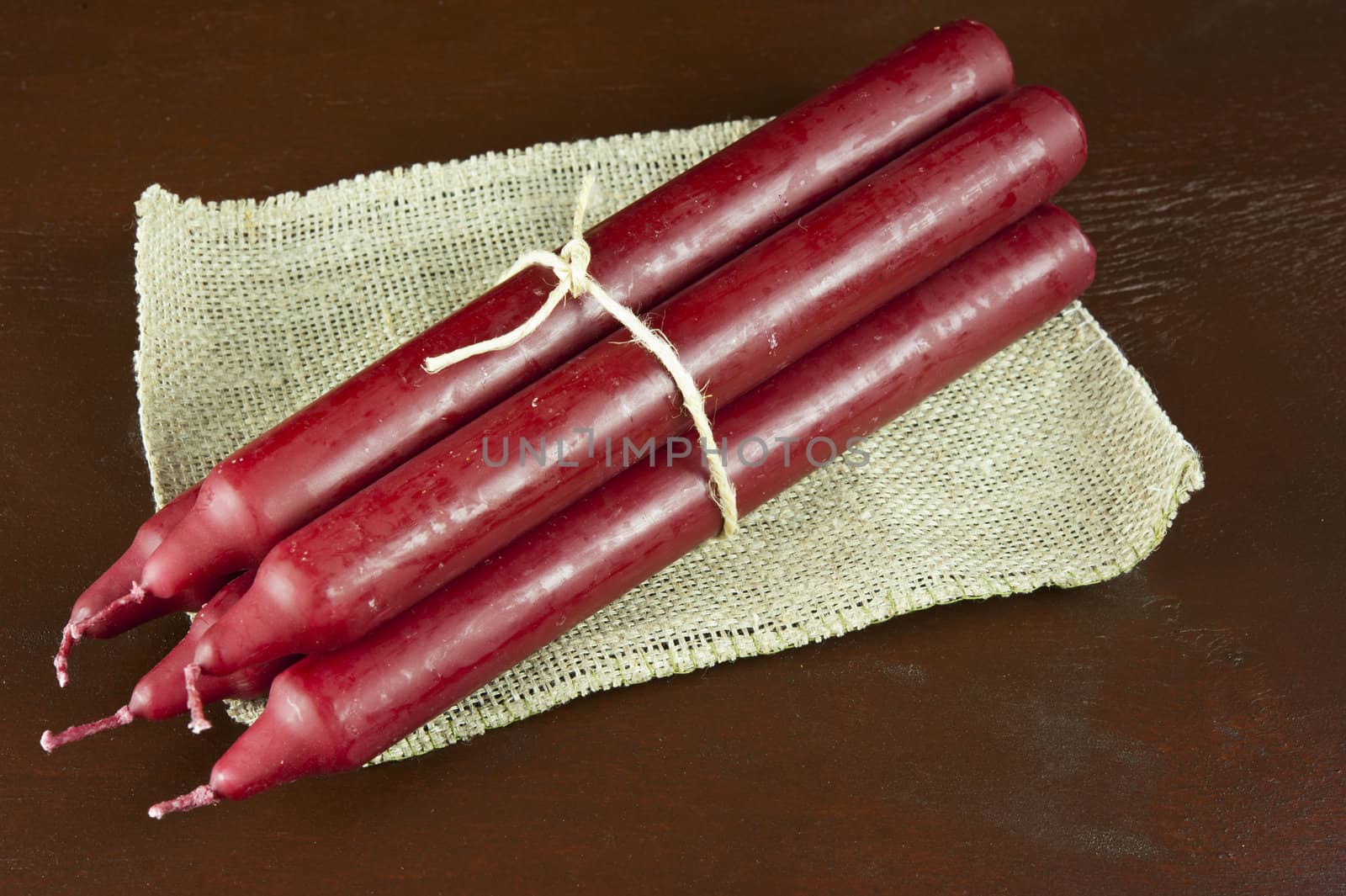 five red candles connected by a rope on sackcloth, dark background