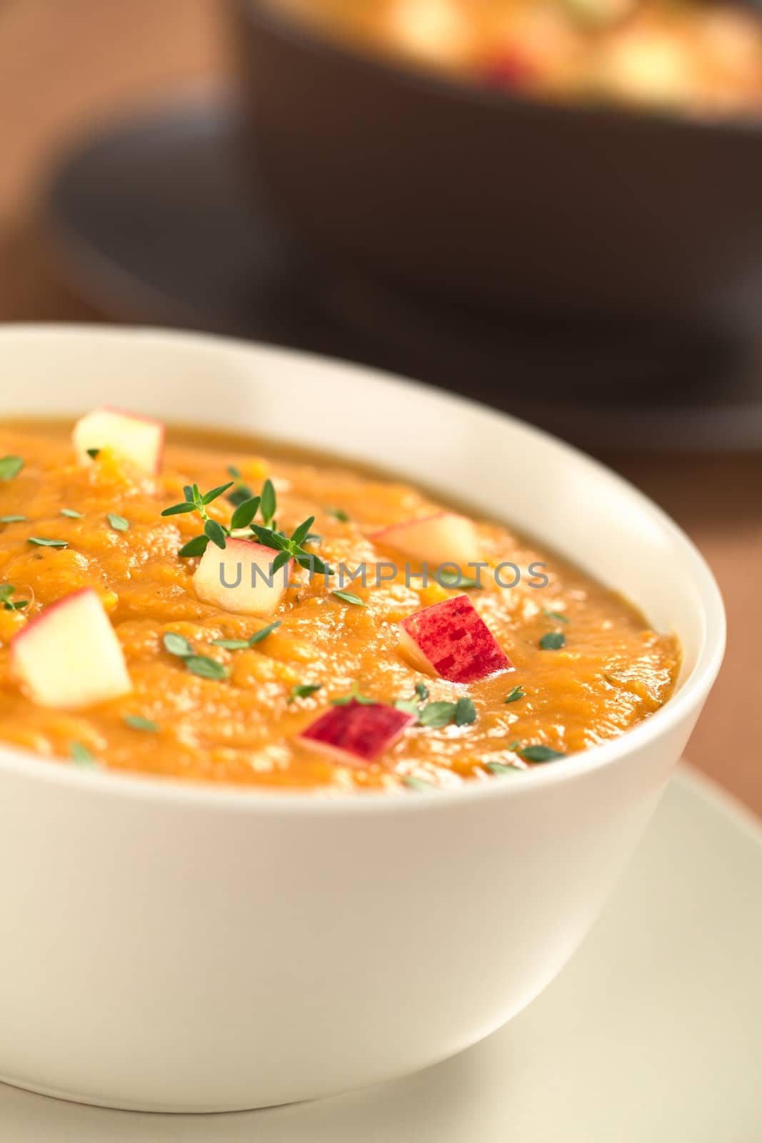 Two bowls of fresh homemade sweet potato and apple soup with thyme (Selective Focus, Focus in the middle of the soup)