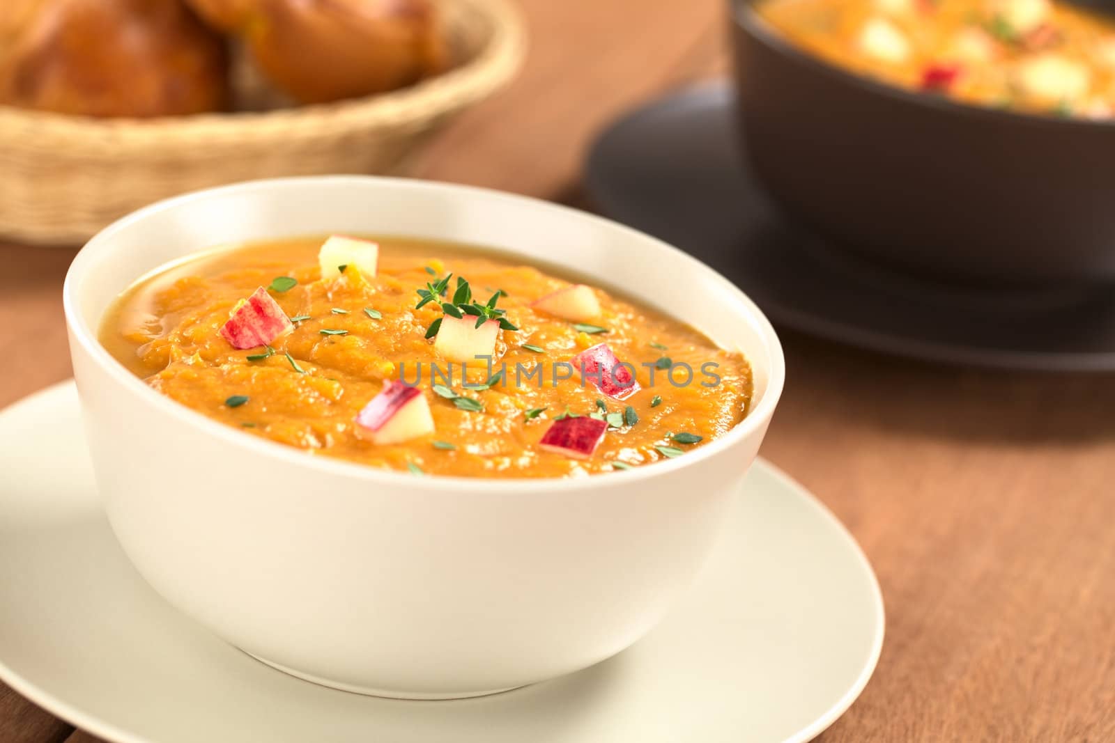 Two bowls of fresh homemade sweet potato and apple soup with thyme (Selective Focus, Focus in the middle of the soup)