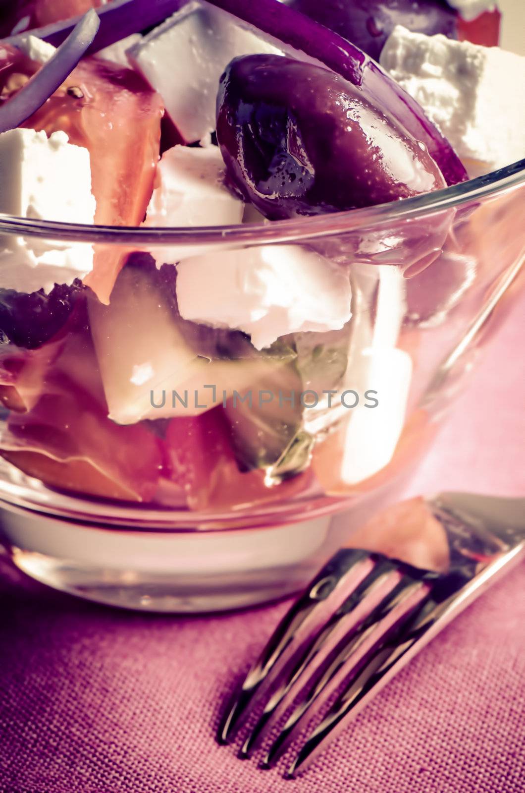 Greek salad in glass dish on napkin.