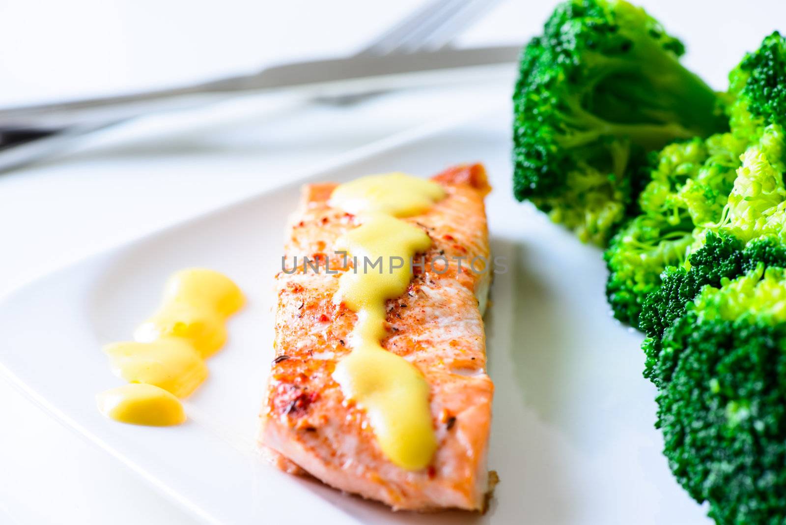 Baked salmon with hollandaise sauce and broccoli on plate