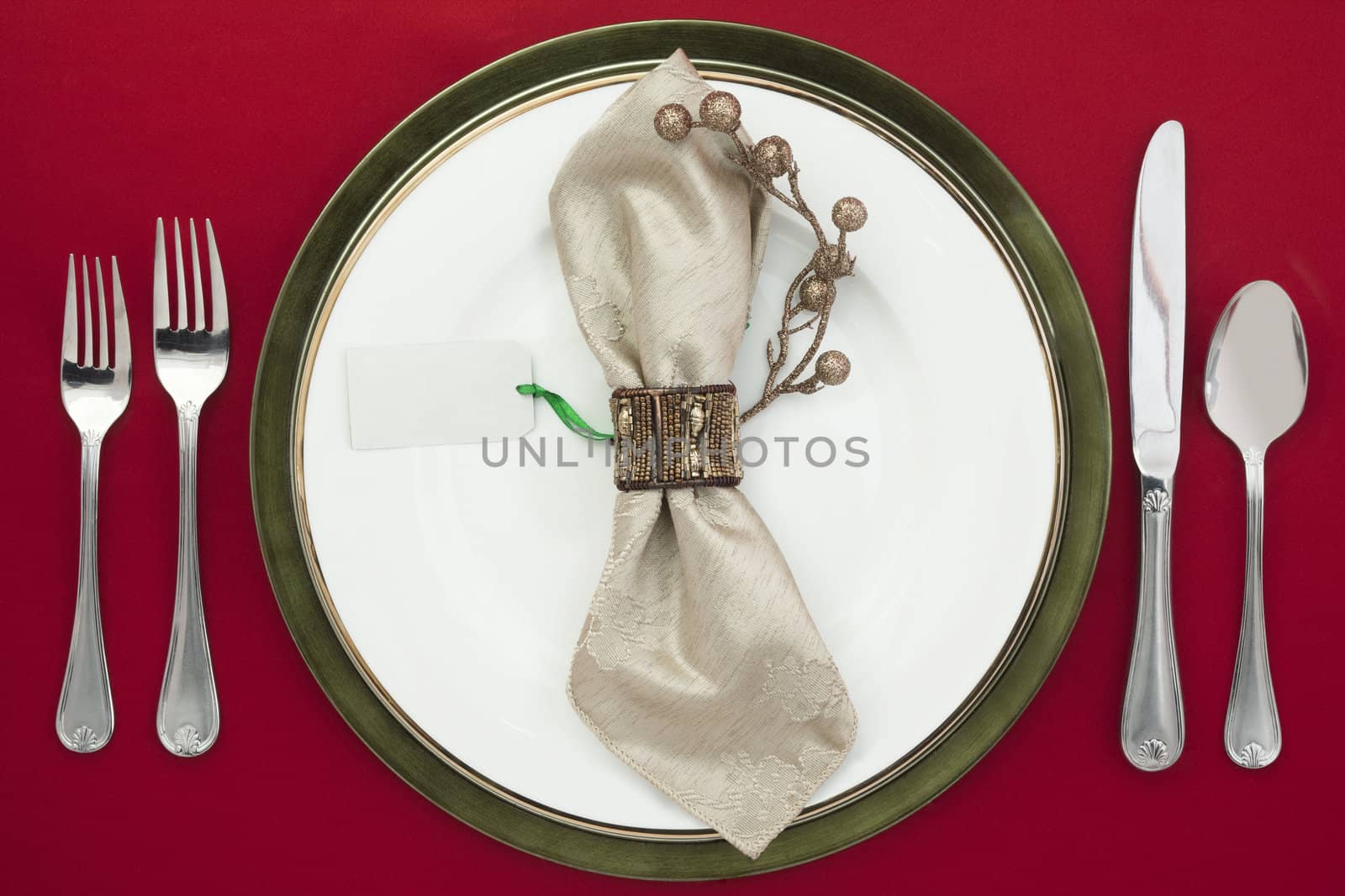 Overhead shot of plate and silverware on red table cloth, white napkin in plate with an empty card.
