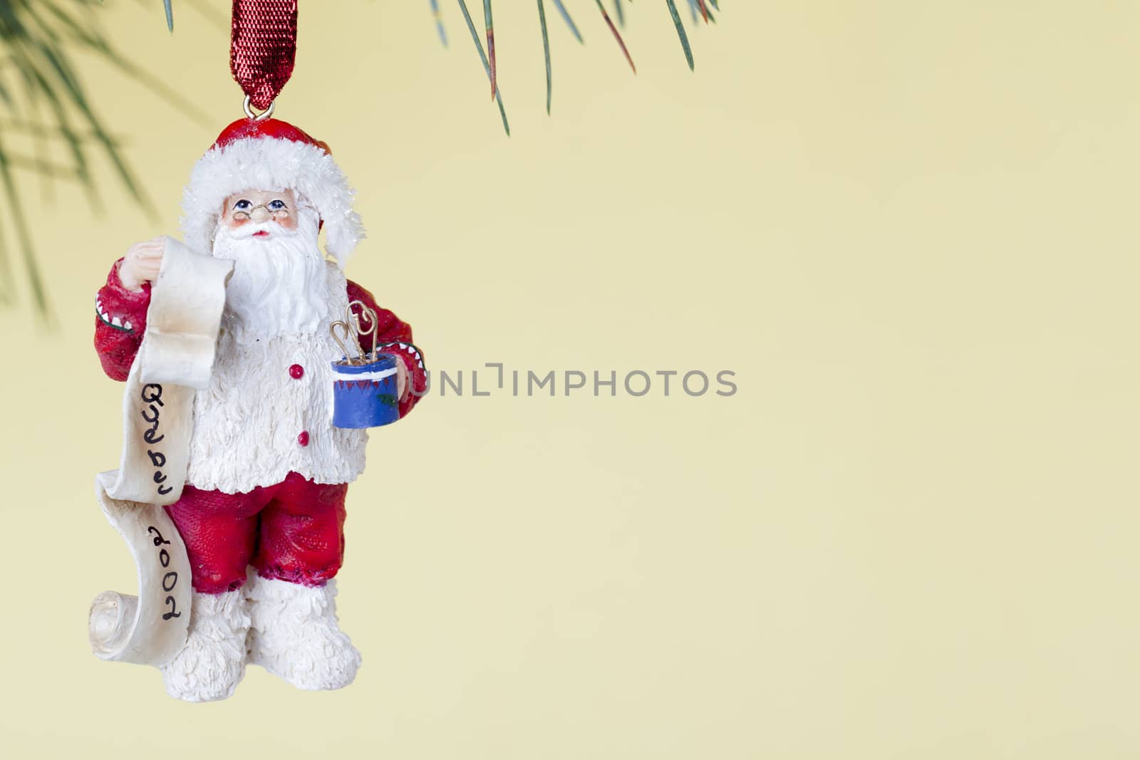 Santa Christmas bauble hanging on Christmas tree against yellow background.