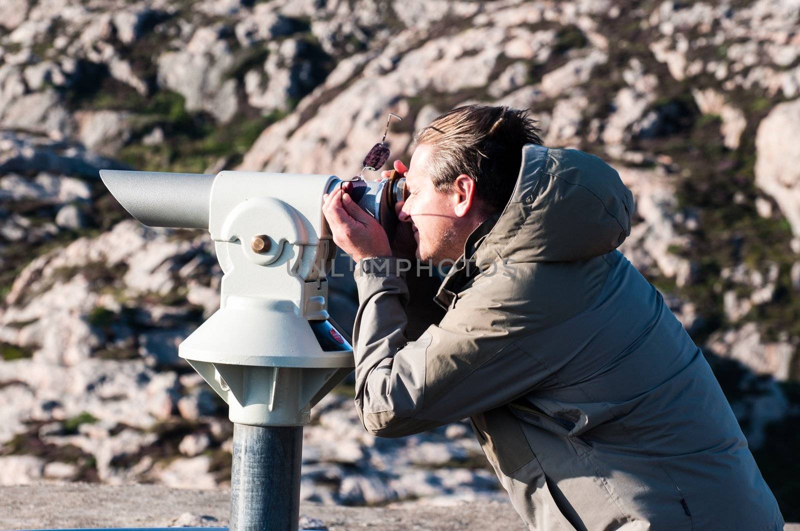 Man observing using spyglass on rocky background