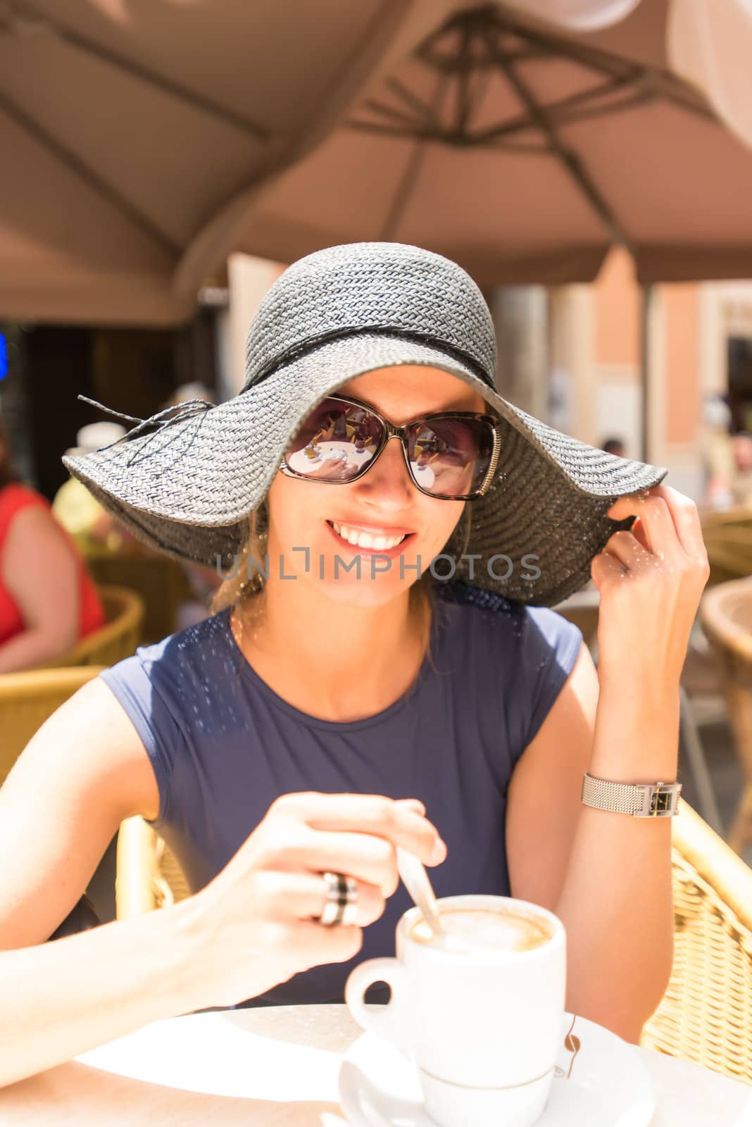 Caucasian cute young woman drinking coffee in cafe by Nanisimova