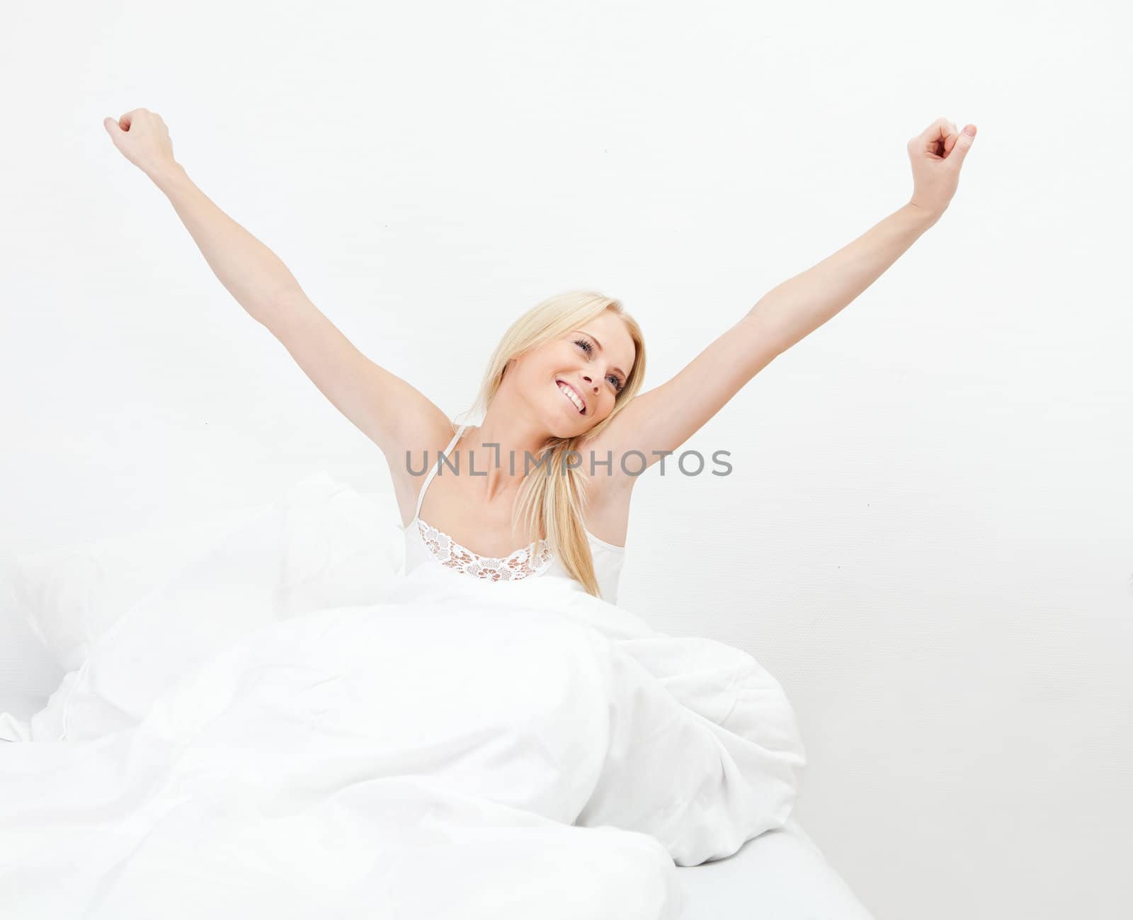 Young happy smiling woman waking up at bedroom