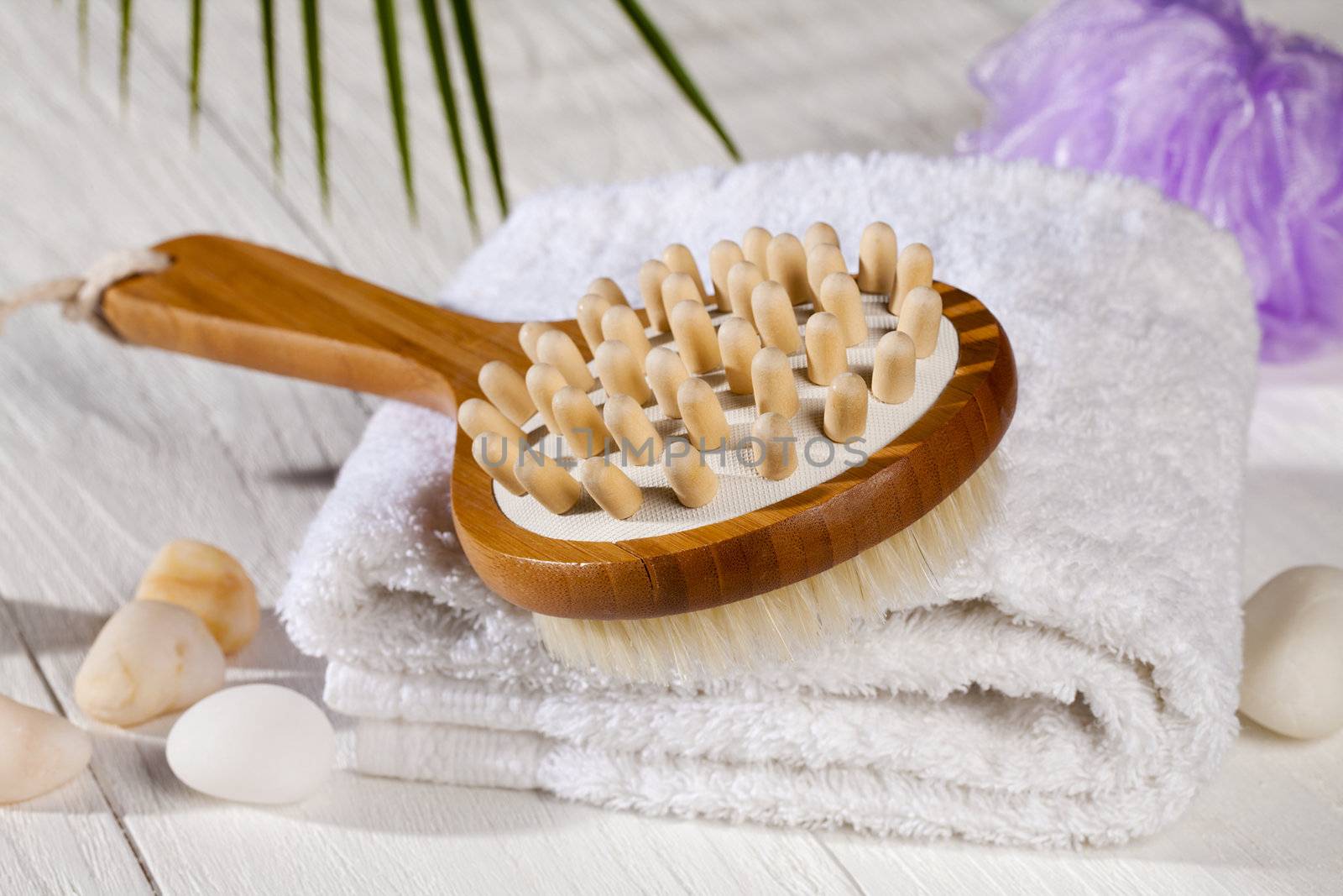 A white towel with a wooden body brush on spa 