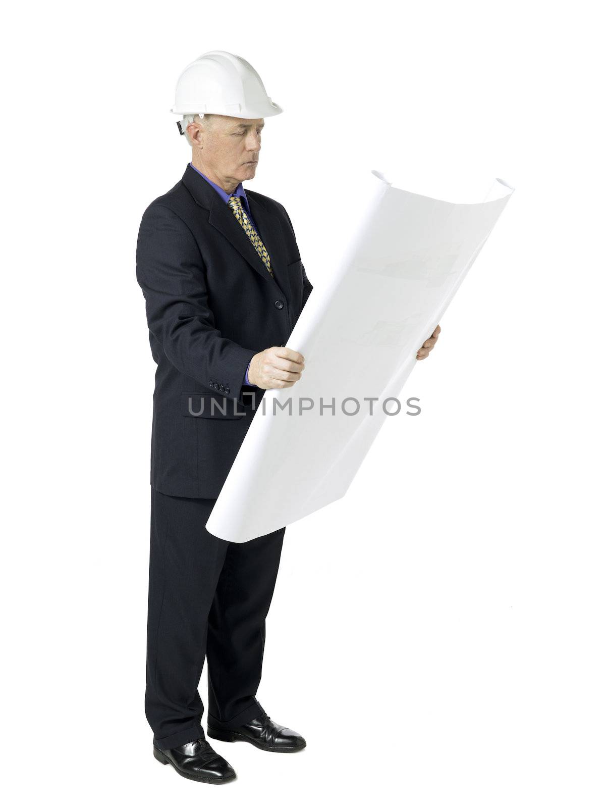 Side view image of an architecture wearing white hard hat and reading blueprint paper. Model: Brian Hayden