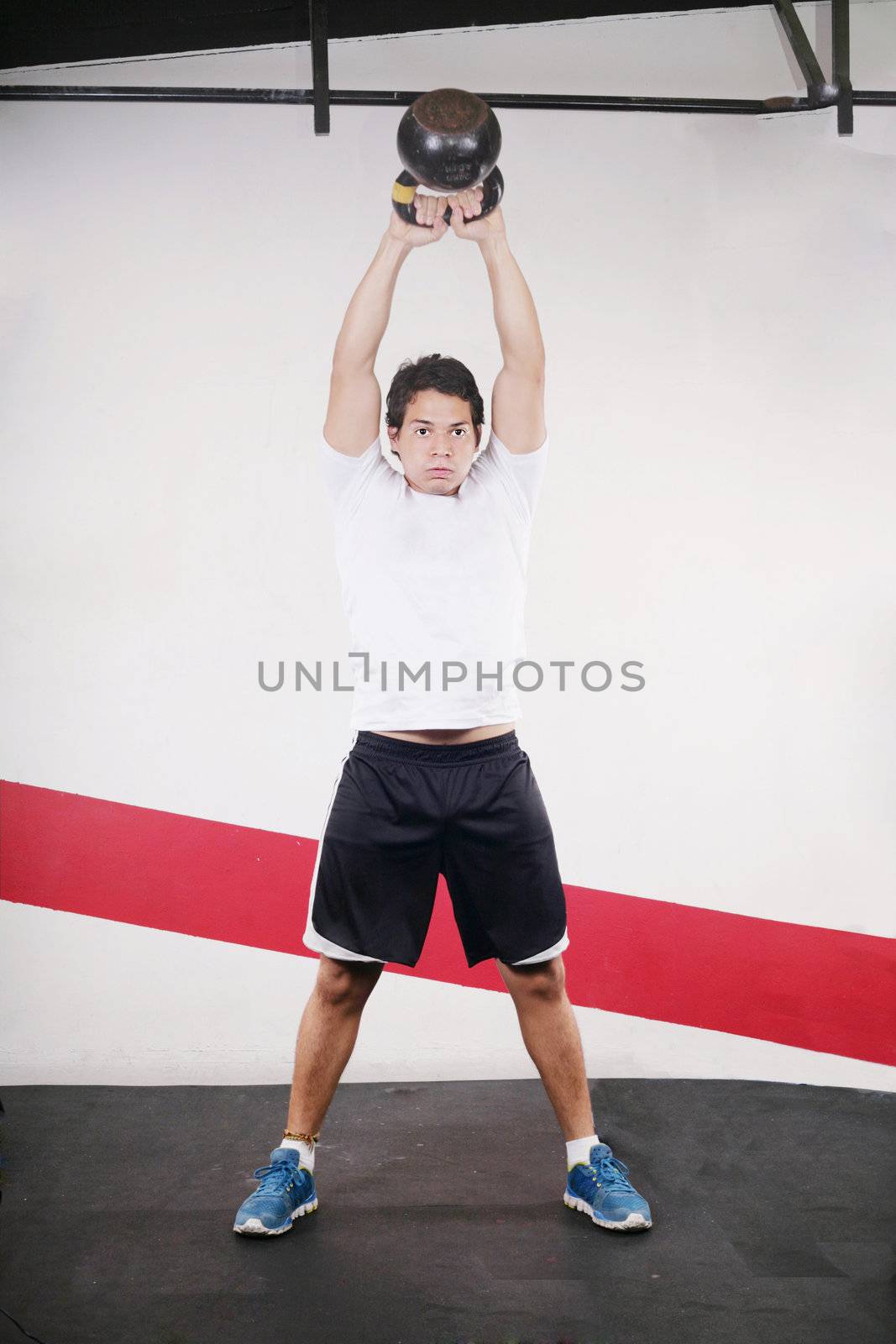 Young man doing kettlebell workout on gym by dacasdo