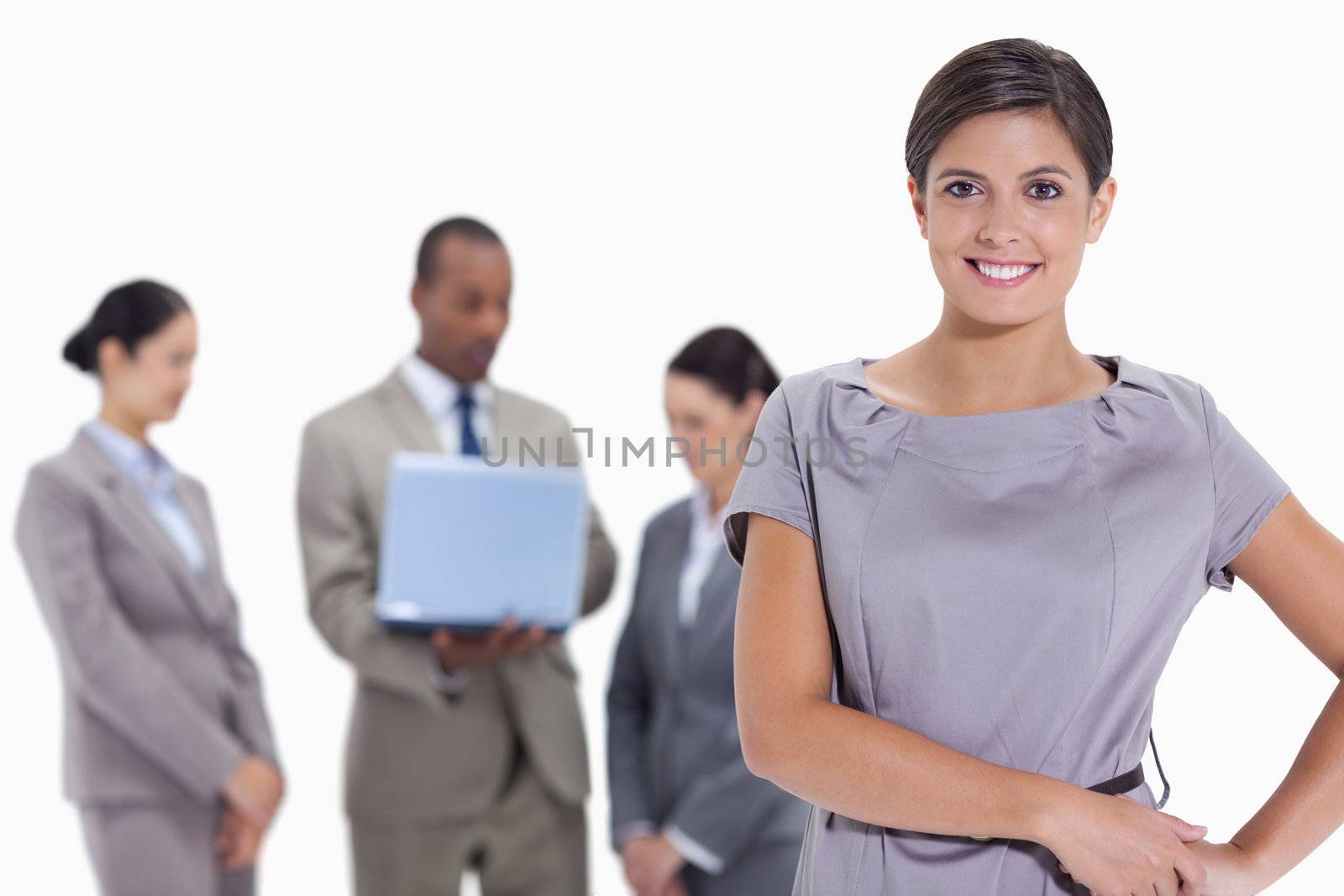 Woman with hands on her hips with business team in the backgroun by Wavebreakmedia