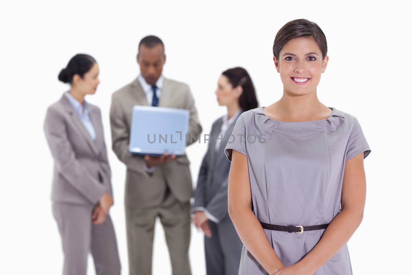 Woman smiling with business team in the background with a laptop by Wavebreakmedia