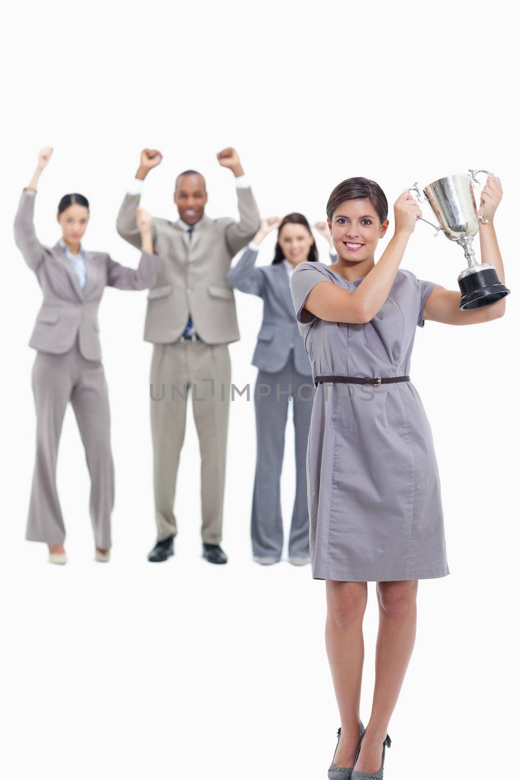 Picture centered on co-workers raising their arms in the background with a woman smiling and holding up a cup 