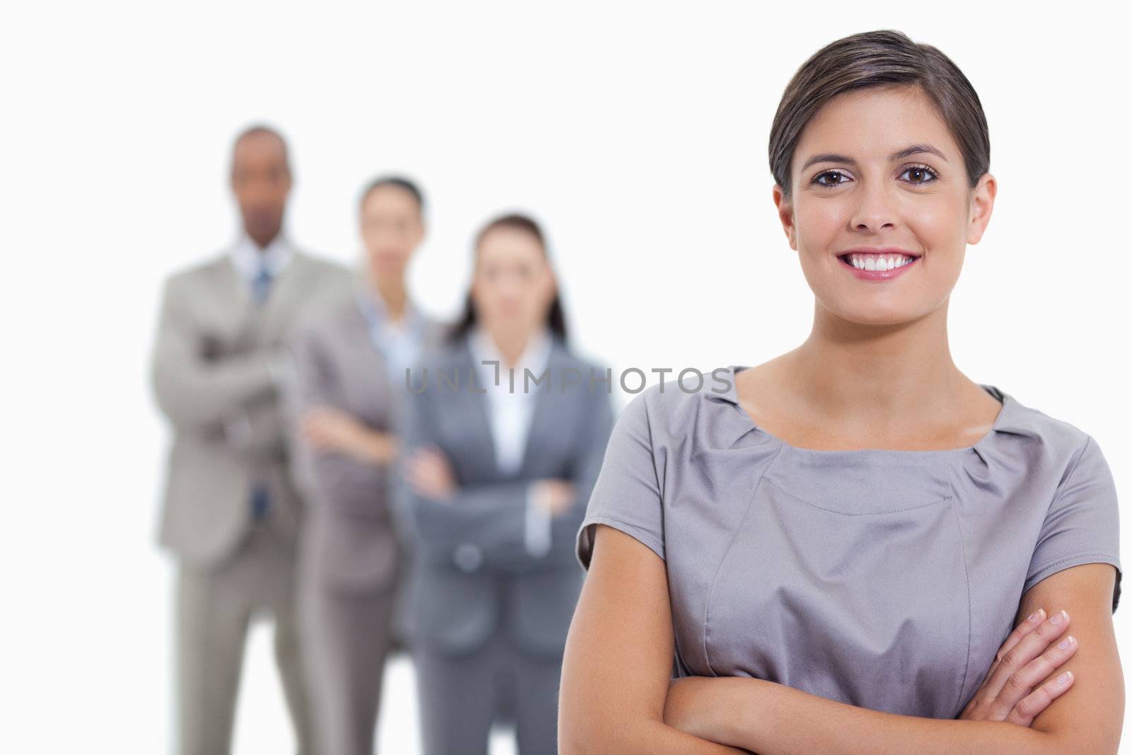 Close-up of a business team crossing their arms and standing behind each other with focus on the foreground woman who is smiling