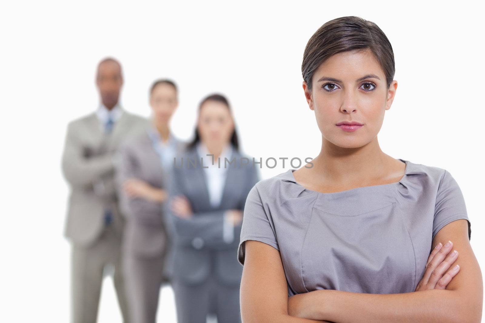 Close-up of a serious business team crossing their arms and standing behind each other with focus on the foreground woman