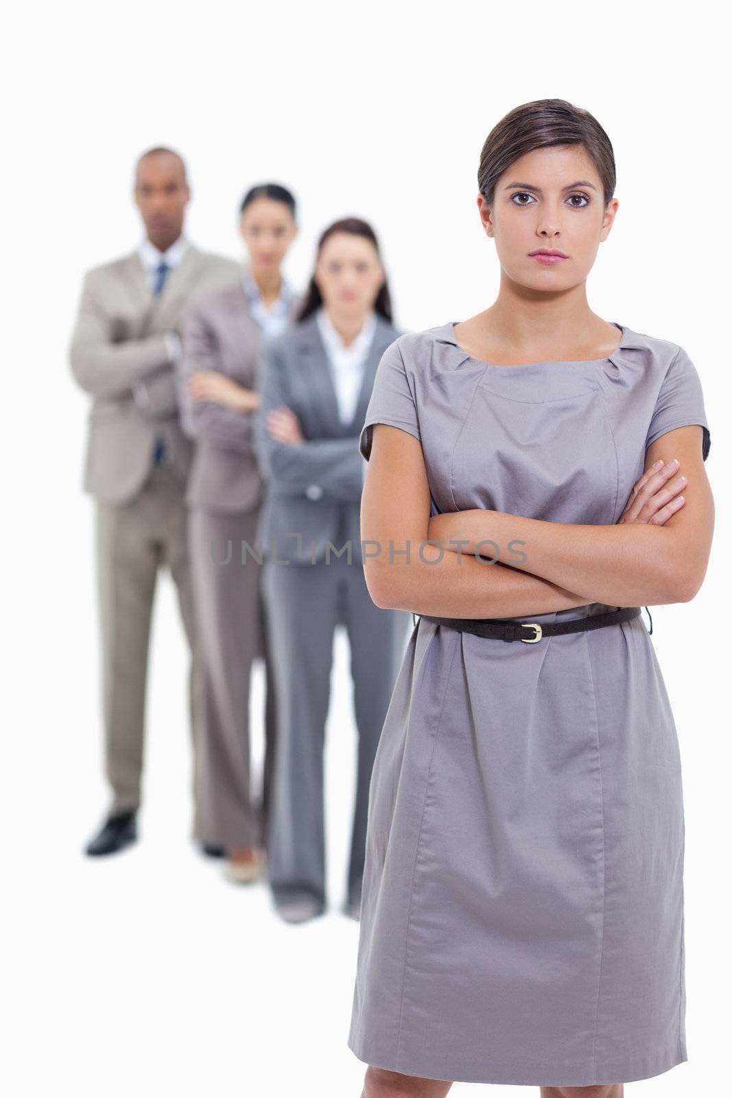 Serious business team crossing their arms and standing behind each other with focus on the foreground woman against white background 
