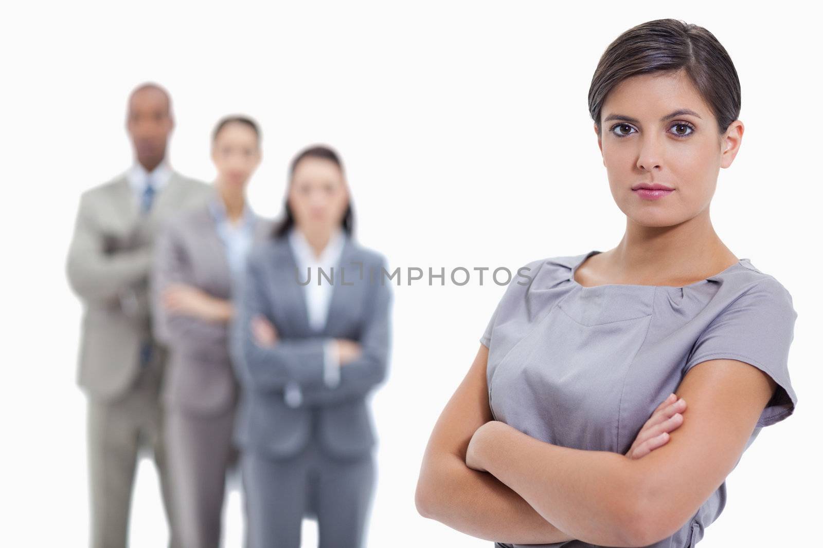 Close-up of a serious businesswoman and a team crossing their arms in background