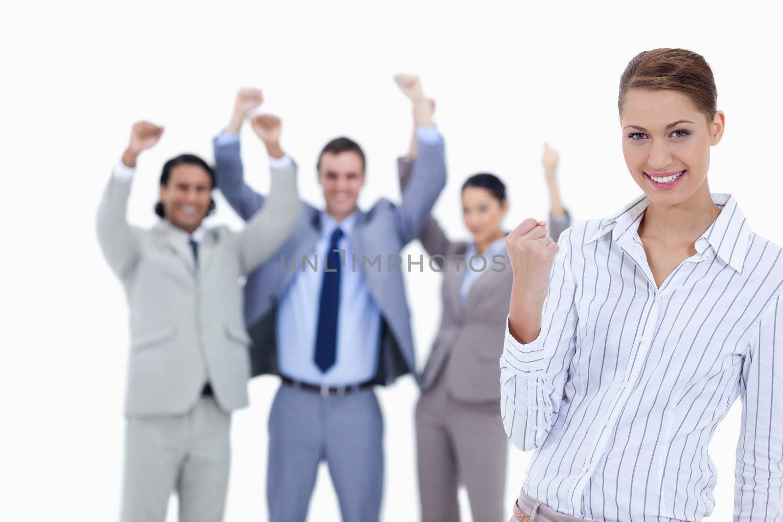 Close-up of a secretary smiling and clenching her fist with enthusiastic business people with their arms raised against white background
