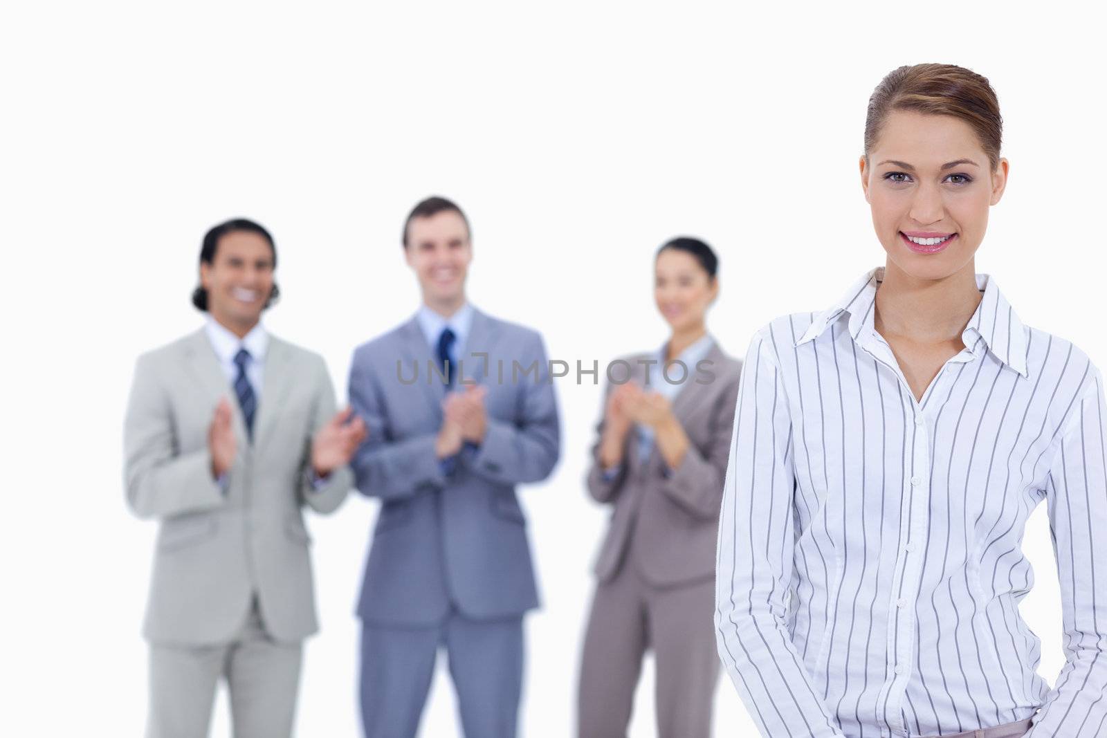 Close-up of a woman smiling with business people applauding in background