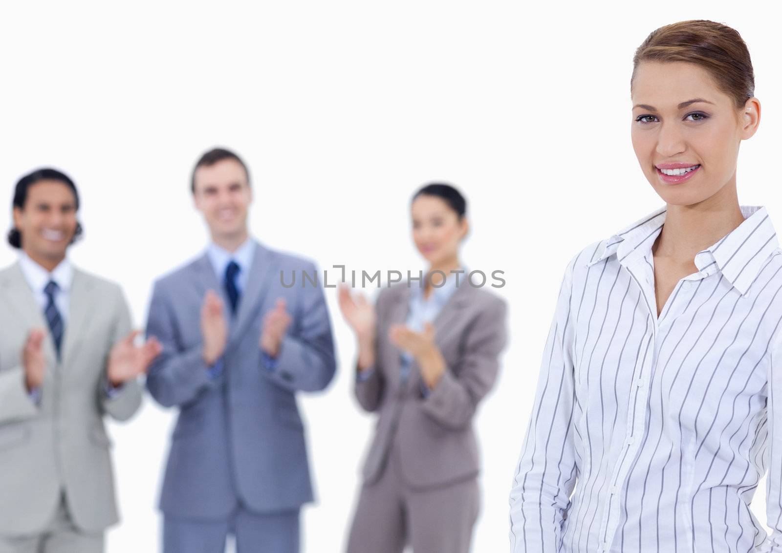 Close-up of a woman smiling with business people applauding while watching her against white background