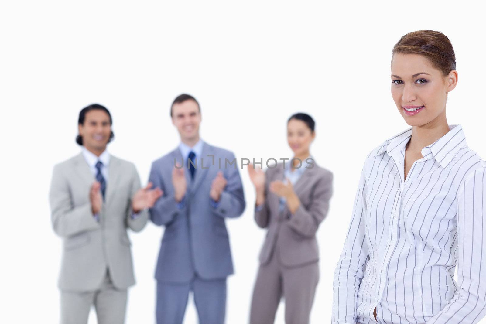 Close-up of a woman with business people applauding while watching her against white background