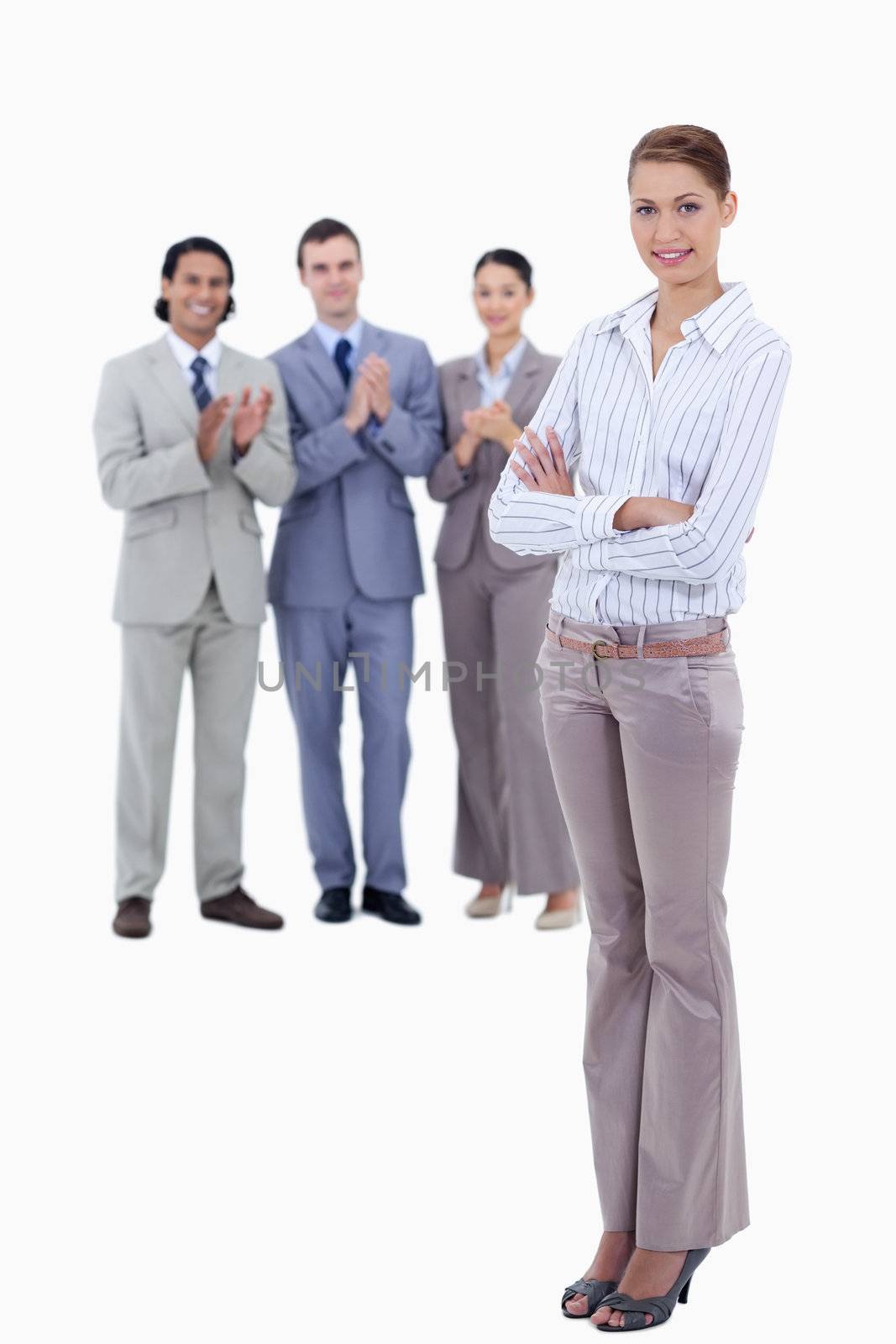 Woman crossing her arms with business people applauding while watching her against white background